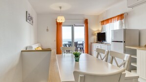 Una cocina moderna con armarios blancos, una mesa de comedor con sillas, un televisor y un refrigerador.