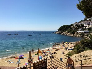 Une plage avec un panneau indiquant l’entrée, un restaurant et un club lounge.