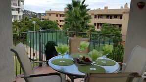 Un balcon avec une table ronde, des chaises et un pot de fleurs.