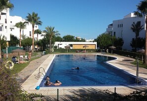 Ein Pool, umgeben von Palmen und modernen Gebäuden.