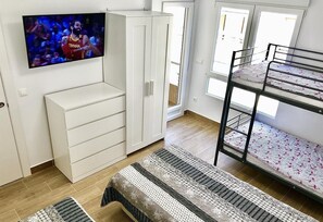 A room with a bunk bed, a TV mounted on a cabinet, a wardrobe, and a patterned rug. - Apartment 'Beach   Jolanta' with Sea View, Wi-Fi and Air Conditioning (Torrevieja)
