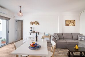 A modern living room with a grey sofa, a dining table with chairs, a coffee table, and decorative wall art.