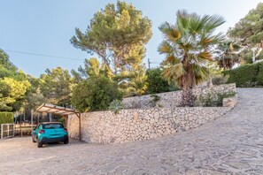 Eine Steinsäule, ein geparktes Auto und eine Pergola.