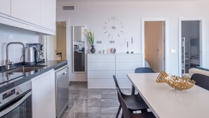 A modern kitchen with a built-in oven, a coffee machine, and a dining area with a white table and chairs. - "Marina view two bedroom apartment" with Sea View, Pool, Terrace & Wi-Fi (Fuengirola)