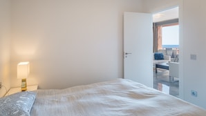A bedroom with a bed, a nightstand, a lamp, and a door leading to a balcony with a view. - "Marina view two bedroom apartment" with Sea View, Pool, Terrace & Wi-Fi (Fuengirola)