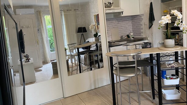 Eine moderne Küche mit einer zentralen Kochinsel, Barhocker und Blick in das angrenzende Schlafzimmer.