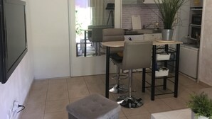 Eine moderne Küche mit Essbereich, einschließlich eines an der Wand montierten Fernsehers, einem Esstisch mit Stühlen und einer Topfpflanze.