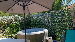 Ein Garten mit Whirlpool, Tisch und Sonnenschirm.