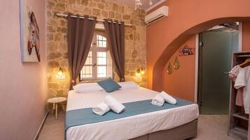 A bedroom with a stone wall, a bed with white linens, a blue throw, and a small round table.