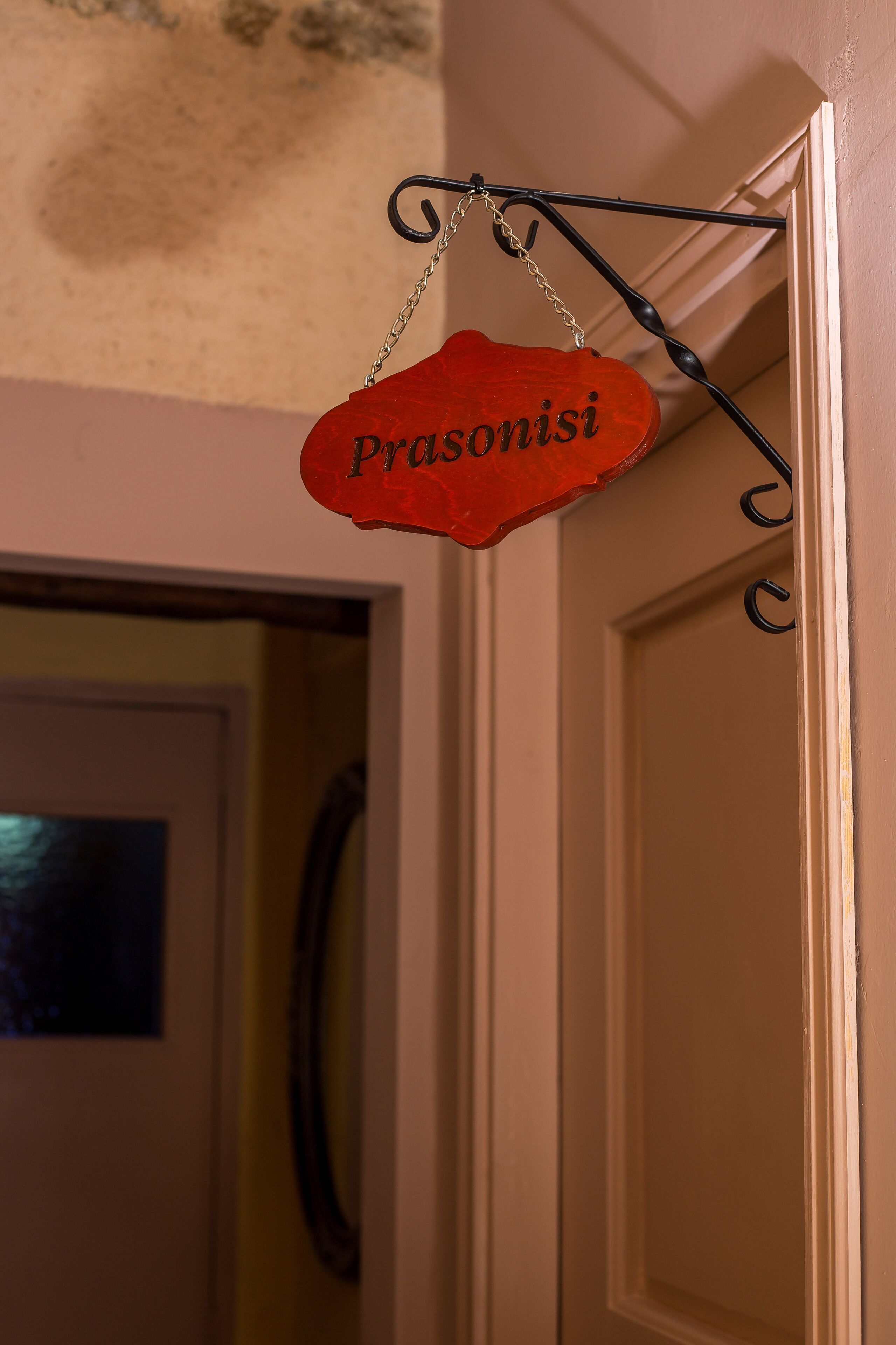 Un letrero rojo con la palabra "Prasonisi" colgado de una estructura metálica negra.