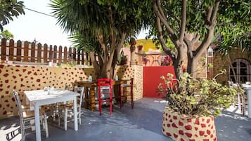 Un patio al aire libre con una mesa y sillas, rodeado por una valla de madera y plantas en macetas.