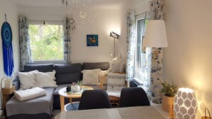 A living room with a sofa, a coffee table, a dining table, and a lamp.