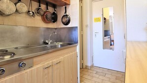 Een keuken met houten kastjes, een roestvrijstalen spoelbak en hangende pannen.