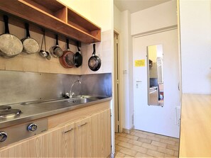 Kitchen area with stove, stainless steel sink, and wooden cabinets.