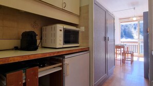 A kitchen with a microwave, a coffee maker, and a sliding door leading to a balcony. - Comfortable studio for 4 with terrace, parking, wifi and pets allowed (Le Dévoluy)