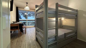 A bunk bed room with a desk and chair, a window with a view of a snowy landscape, and a hanging light fixture. - Comfortable studio for 4 with terrace, parking, wifi and pets allowed (Le Dévoluy)