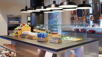 Un espace buffet proposant divers plats, une vitrine réfrigérée et des plantes suspendues.