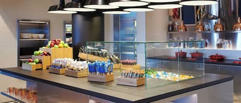A buffet area with various food items, a glass display case, and hanging plants.