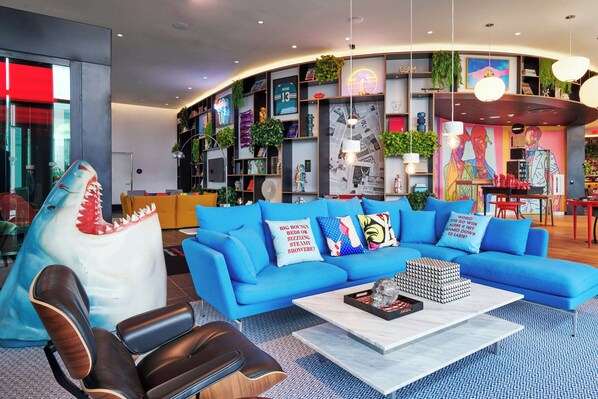 A modern living room with a blue sofa, a shark decoration, and a coffee table. - citizenM Miami Worldcenter (Miami)