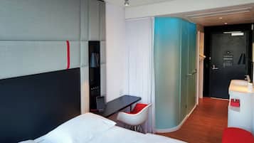 Een moderne hotelkamer met een bed, een bureau, een stoel en een badkamer.