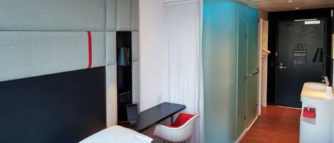 Una habitación de hotel moderna con cama, escritorio, silla y baño.