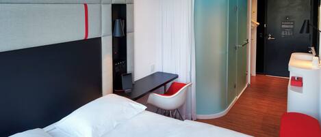 Une chambre d’hôtel moderne avec un grand lit, un bureau et un petit coin salon.