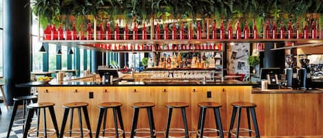 A bar area with a checkered floor, wooden bar counter, and black stools.