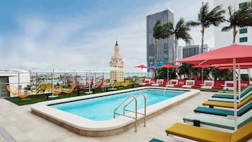 Una piscina al aire libre, sombrillas, sillones reclinables de piscina