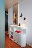 Uma casa de banho moderna com toucador branco, candeeiro preto suspenso na parede e caixa de lenços vermelha.