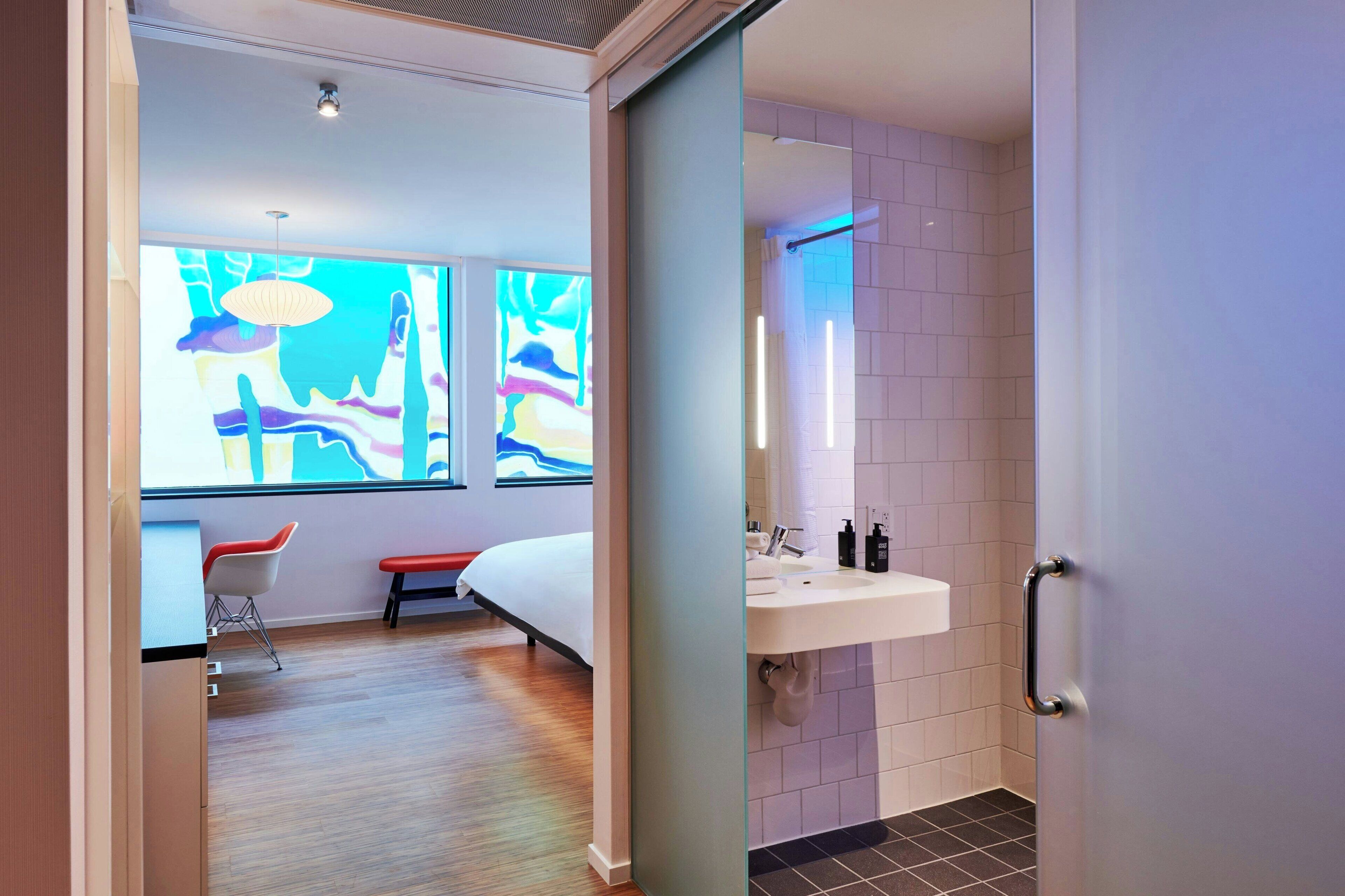 A modern bathroom with a large mirror, a sink, and a shower area.