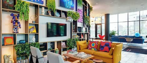 Een moderne woonkamer met een grote flatscreen televisie, comfortabele zithoek en een levendig kleurenschema.
