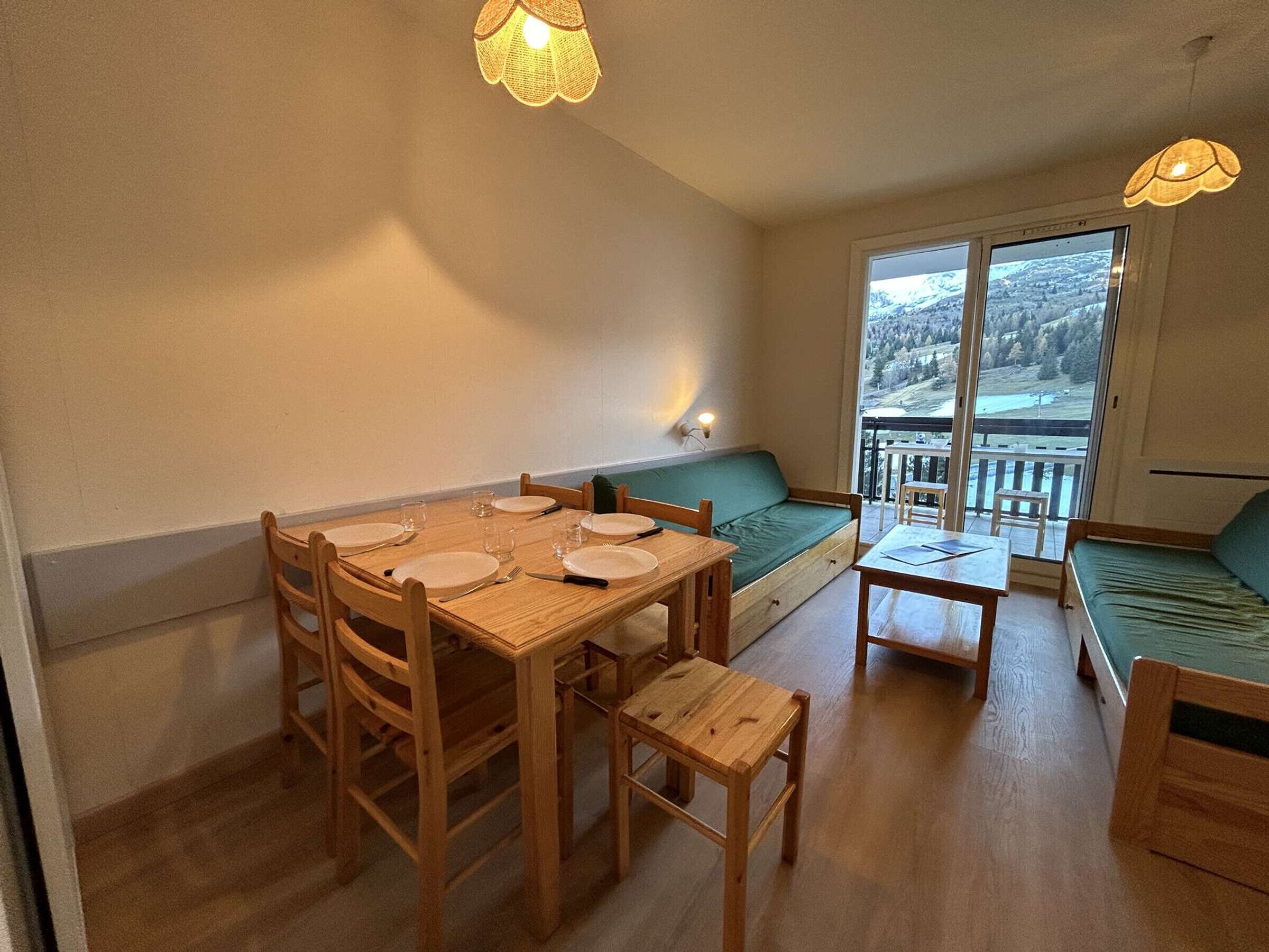 Un'accogliente zona pranzo con tavolo e sedie in legno, un divano verde e un balcone con vista sulla campagna.