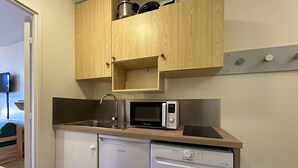A compact kitchen with wooden cabinets, a microwave, and a dishwasher.