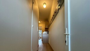 A narrow hallway with wooden flooring and a staircase on the right.