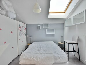 A modern bedroom with a skylight, a bed, a chair, and a wardrobe.
