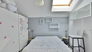 A modern bedroom with a skylight, a bed, a chair, and a wardrobe.