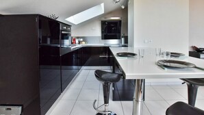 A modern kitchen with a central island, black cabinetry, and stainless steel appliances.