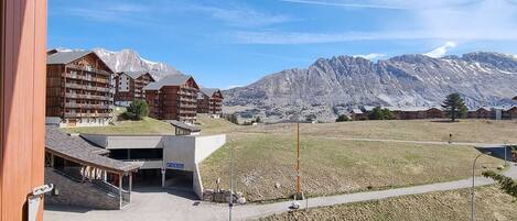 A hotel with multiple wooden buildings, a parking area, and a mountain backdrop.