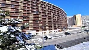 A multi-story hotel with balconies, a parking lot, and a snow-covered landscape.