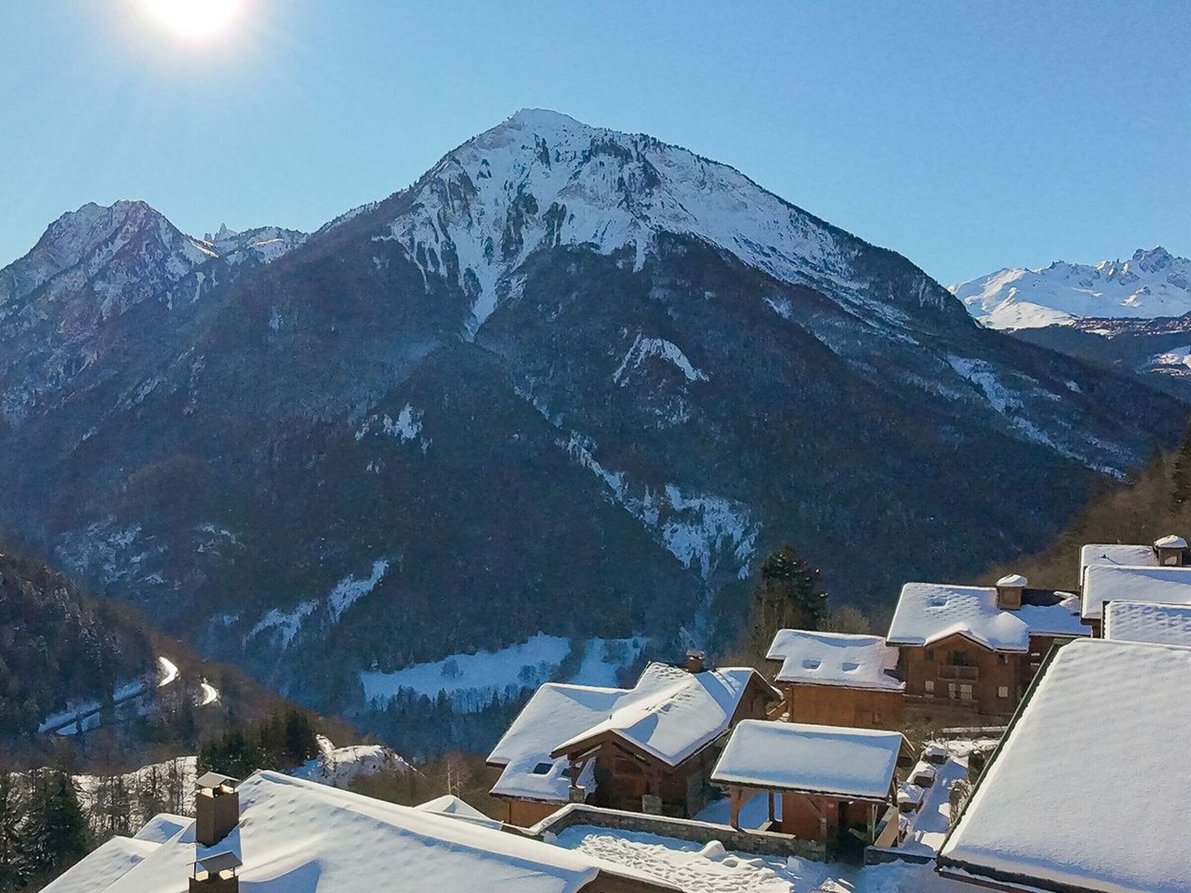 A mountain village with snow-covered houses and a prominent peak in the background.