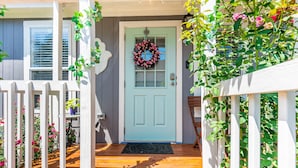 A light blue door with a wreath, a white picket fence, and a wooden porch. - - Adorable Guest House in South Tyler - (Tyler)