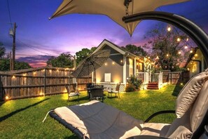 A cozy backyard with a patio, string lights, and a lawn chair. - - Adorable Guest House in South Tyler - (Tyler)