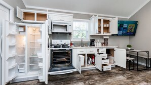 A compact kitchen with built-in appliances, a dining area, and a flat-screen TV mounted on the wall. - - Adorable Guest House in South Tyler - (Tyler)