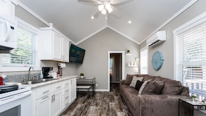 A modern kitchen with white cabinets, a dining area with a table and chairs, a brown sofa, and a ceiling fan. - - Adorable Guest House in South Tyler - (Tyler)