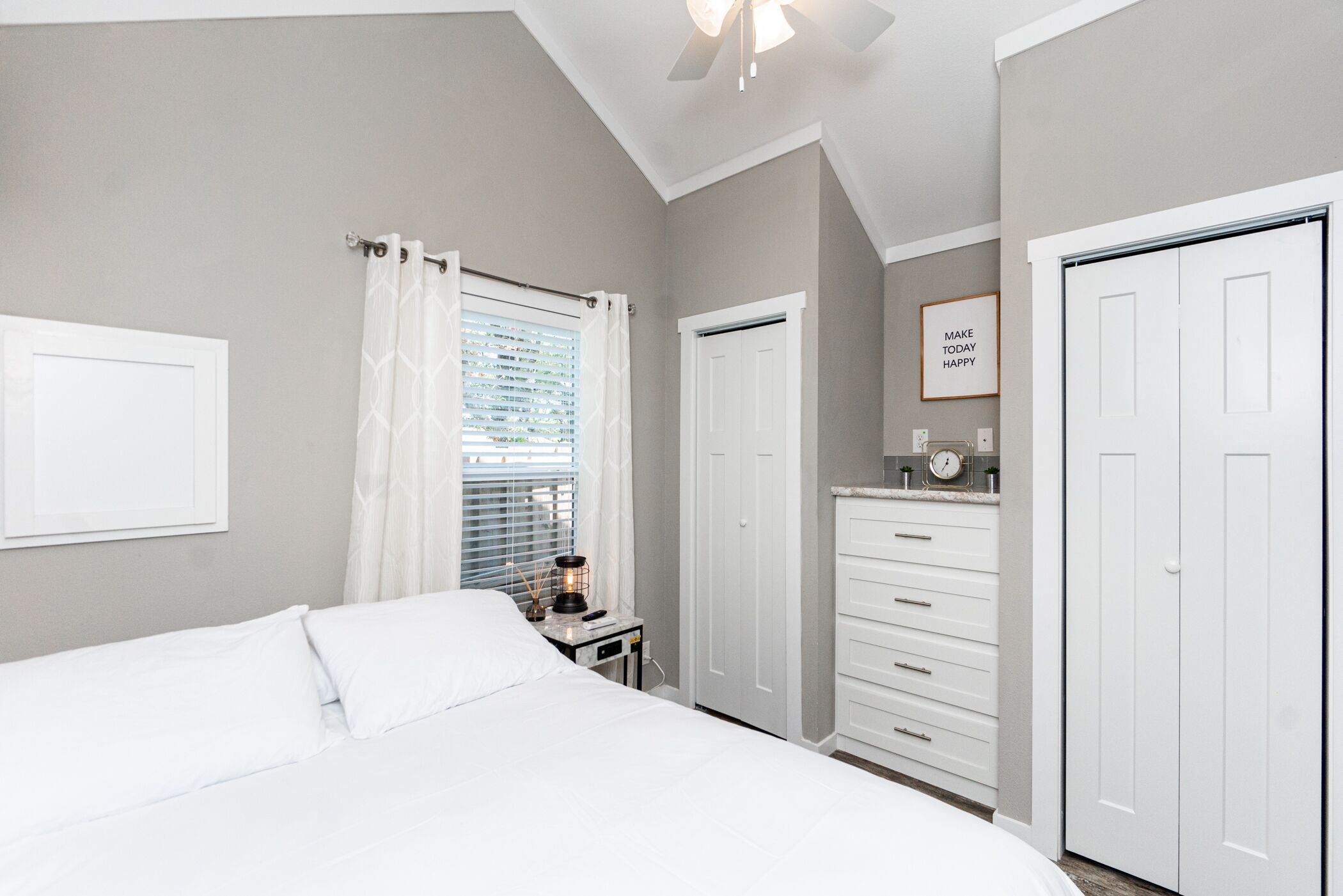 A bedroom with a bed, a nightstand, a dresser, and a closet.