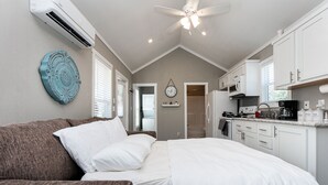 A compact hotel room with a bed, a sofa, a kitchenette, and a ceiling fan. - - Adorable Guest House in South Tyler - (Tyler)