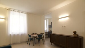 Un salon moderne comprenant un coin repas, un canapé et un meuble sur lequel est posée une sculpture.