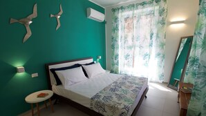 Une chambre à coucher comprenant un lit, une petite table, un miroir et un climatiseur fixé au mur.