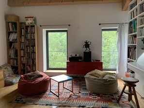 Un coin lecture confortable avec une bibliothèque, un meuble rouge et un fauteuil en forme de sac à haricots.