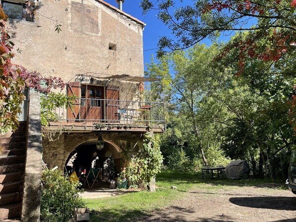Un bâtiment rustique en pierre, avec un pont en bois menant à une entrée abritée.